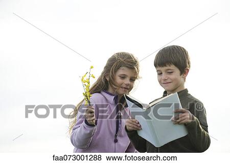 Stock Photo - Children reading together outdoors. Fotosearch