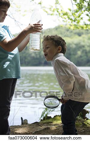Picture - Children studying fish in water bottle. Fotosearch