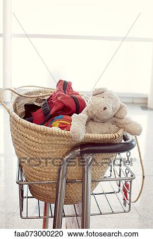 Stock Image - Child's teddy bear and other belongings in basket. Fotosearch