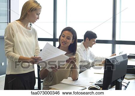 Colleagues reviewing documents together View Large Photo Image Stock Photograph - Colleagues reviewing documents together. Fotosearch