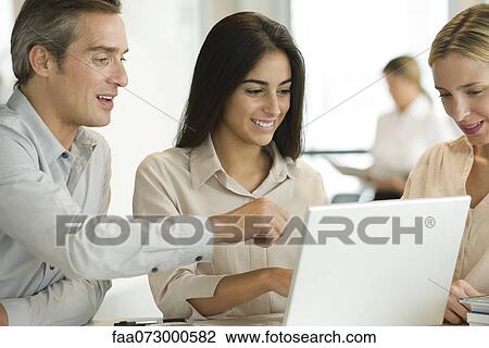 Stock Image - Colleagues working together on laptop computer. Fotosearch