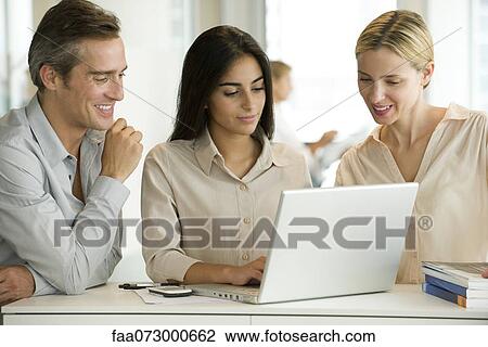 Colleagues working together on laptop computer View Large Photo Image Stock Image - Colleagues working together on laptop computer. Fotosearch