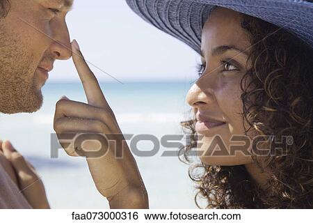 Couple at the beach, woman touching man's nose View Large Photo Image Stock Photograph - Couple at the beach, woman touching man's nose. Fotosearch