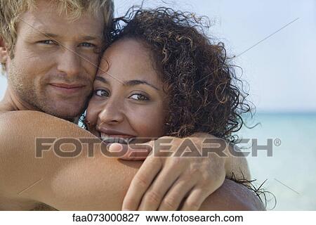 Stock Photo - Couple embracing at the beach, portrait. Fotosearch