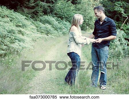 Stock Photography - Couple holding hands on path through countryside. Fotosearch