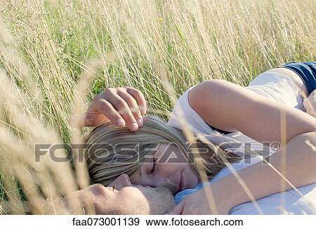 Couple lying together in field of tall grass View Large Photo Image Stock Photo - Couple lying together in field of tall grass. Fotosearch