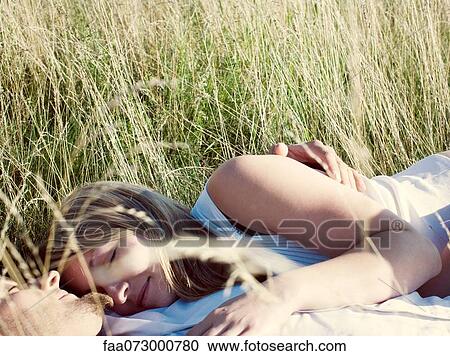 Stock Image - Couple napping together in tall grass. Fotosearch