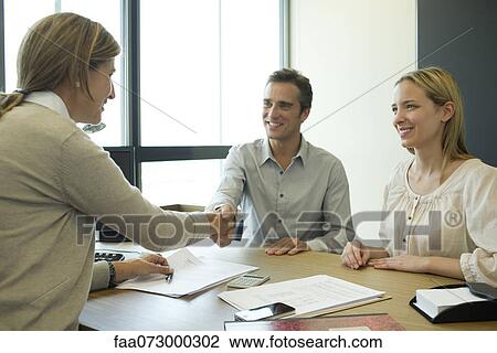 Couple shaking hands with businesswoman in office View Large Photo Image Stock Image - Couple shaking hands with businesswoman in office. Fotosearch