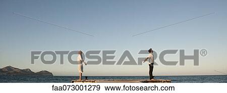 Couple standing back to back on pier, arms out stretched and eyes closed View Large Photo Image Stock Photo - Couple standing back to back on pier, arms out stretched and eyes closed. Fotosearch