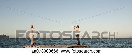 Couple standing on pier, man talking to woman through megaphone View Large Photo Image Stock Photograph - Couple standing on pier, man talking to woman through megaphone. Fotosearch