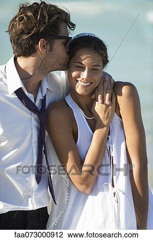 Stock Image - Couple together outdoors, man kissing woman's forehead. Fotosearch