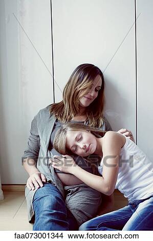 Picture - Daughter listening to pregnant mother's abdomen, portrait. Fotosearch