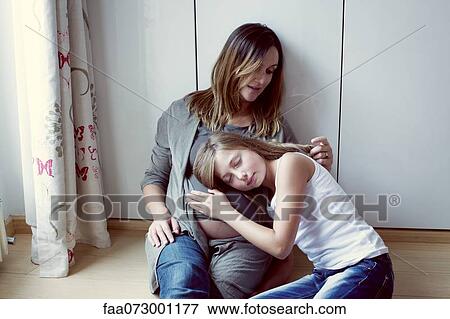 Daughter listening to pregnant mother's abdomen, mother caressing daughter's hair, portrait View Large Photo Image Stock Photo - Daughter listening to pregnant mother's abdomen, mother caressing daughter's hair, portrait. Fotosearch