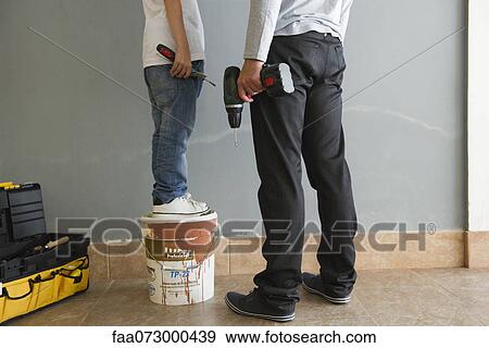 Stock Photo - Father and son doing home improvement, low section. Fotosearch