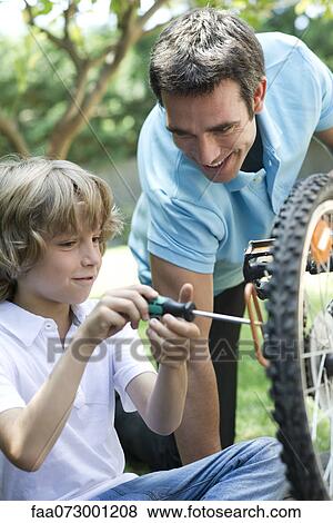 Stock Photo - Father helping son repair bicycle. Fotosearch