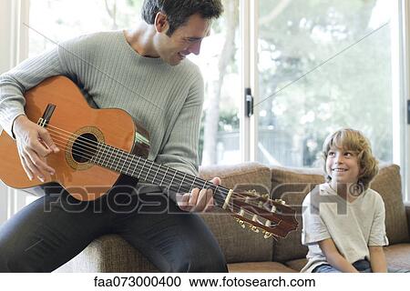 Stock Image - Father playing guitar for son. Fotosearch