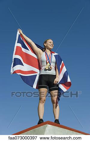 Female athlete being honored on podium, holding up British flag View Large Photo Image Stock Photo - Female athlete being honored on podium, holding up British flag. Fotosearch