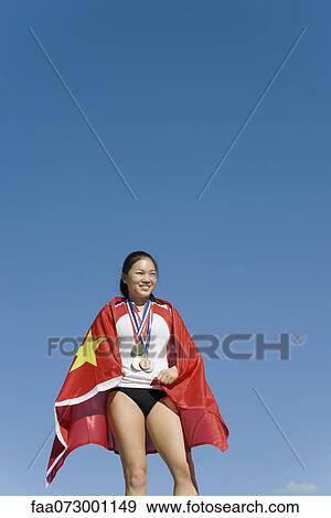 Stock Photo - Female athlete on winner's podium, wrapped in Chinese flag. Fotosearch