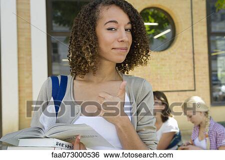 Stock Photograph - Female college student giving thumbs up sign, portrait. Fotosearch