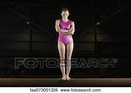 Female gymnast standing on balance beam View Large Photo Image Stock Photograph - Female gymnast standing on balance beam. Fotosearch