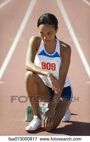 Stock Photo - Female runner crouched at starting line. Fotosearch