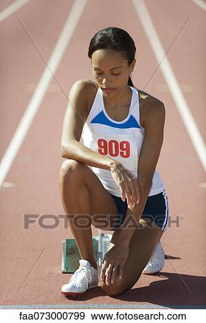 Female runner crouching at starting line with eyes closed View Large Photo Image Stock Photo - Female runner crouching at starting line with eyes closed. Fotosearch