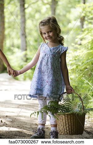 Stock Photo - Girl carrying basket filled with fern fronds. Fotosearch