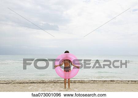 Girl holding inflatable ring on beach, rear view View Large Photo Image Stock Photograph - Girl holding inflatable ring on beach, rear view. Fotosearch