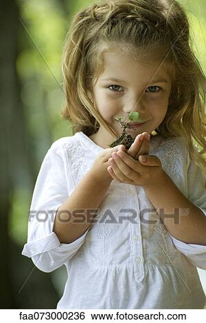 Stock Photograph - Girl holding seedling, portrait. Fotosearch