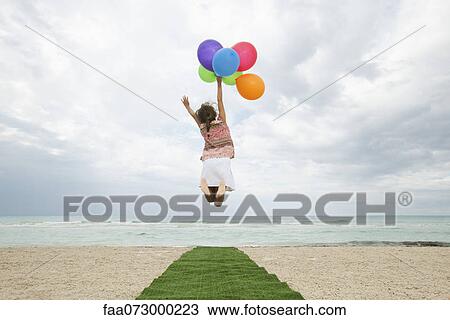Girl jumping in air with bunch of colorful balloons, rear view View Large Photo Image Stock Image - Girl jumping in air with bunch of colorful balloons, rear view. Fotosearch