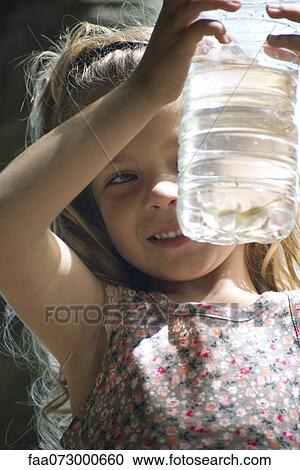 Girl looking at bottle of water View Large Photo Image Stock Image - Girl looking at bottle of water. Fotosearch