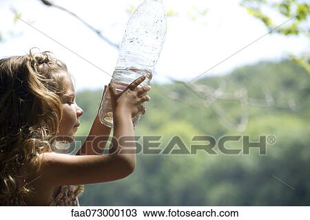 Stock Image - Girl looking at fish in water bottle. Fotosearch