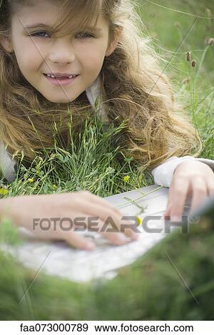 Stock Photo - Girl lying in grass, using laptop computer, portrait. Fotosearch