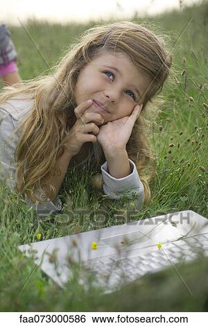 Girl lying in grass with laptop computer, daydreaming View Large Photo Image Stock Photograph - Girl lying in grass with laptop computer, daydreaming. Fotosearch