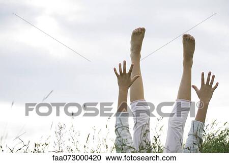 Girl lying on back in tall grass with arms and legs raised in the air View Large Photo Image Stock Image - Girl lying on back in tall grass with arms and legs raised in the air. Fotosearch