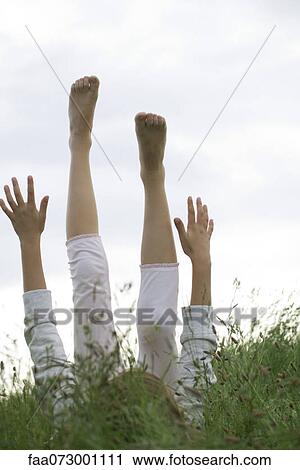 Girl lying on back in tall grass with arms and legs raised in the air View Large Photo Image Stock Image - Girl lying on back in tall grass with arms and legs raised in the air. Fotosearch