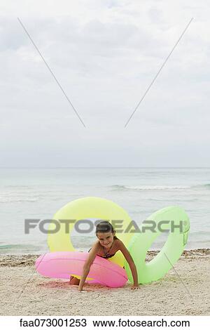 Girl playing with inflatable rings on beach View Large Photo Image Stock Image - Girl playing with inflatable rings on beach. Fotosearch