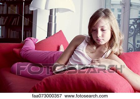 Girl reclining on couch reading book View Large Photo Image Stock Photo - Girl reclining on couch reading book. Fotosearch