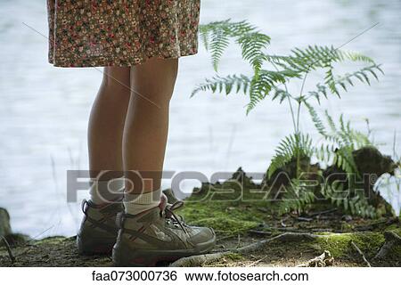 Stock Photograph - Girl standing at water's edge, low section. Fotosearch