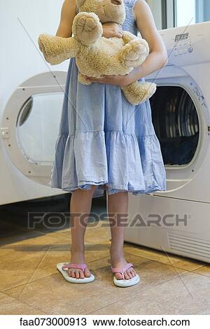 Girl standing in front of dryer, holding teddy bear View Large Photo Image Stock Image - Girl standing in front of dryer, holding teddy bear. Fotosearch