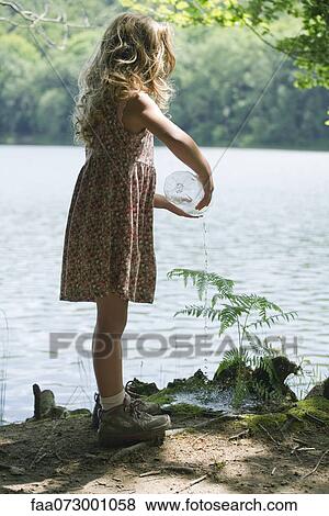 Girl watering plant View Large Photo Image Stock Photo - Girl watering plant. Fotosearch