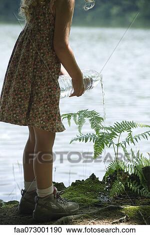 Girl watering plant with bottle of water View Large Photo Image Stock Image - Girl watering plant with bottle of water. Fotosearch