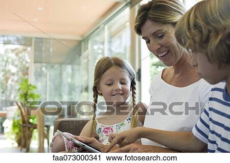 Grandmother and grandchildren using digital tablet View Large Photo Image Stock Image - Grandmother and grandchildren using digital tablet. Fotosearch