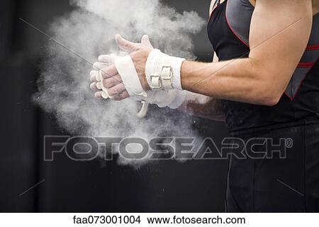 Gymnast applying chalk power to hands in preparation View Large Photo Image Picture - Gymnast applying chalk power to hands in preparation. Fotosearch