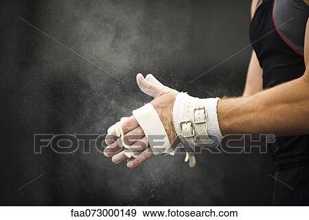 Stock Photo - Gymnast applying chalk power to hands in preparation. Fotosearch