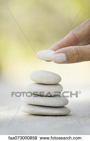 Hand stacking pebbles View Large Photo Image Stock Photo - Hand stacking pebbles. Fotosearch