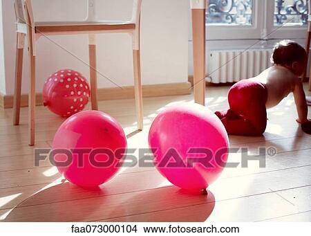 Infant crawling away from ballons on floor View Large Photo Image Picture - Infant crawling away from ballons on floor. Fotosearch