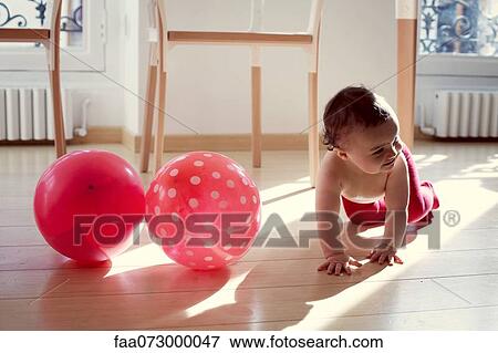 Stock Photo - Infant crawling by pink ballons. Fotosearch