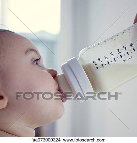 Picture - Infant drinking milk from bottle, side view. Fotosearch