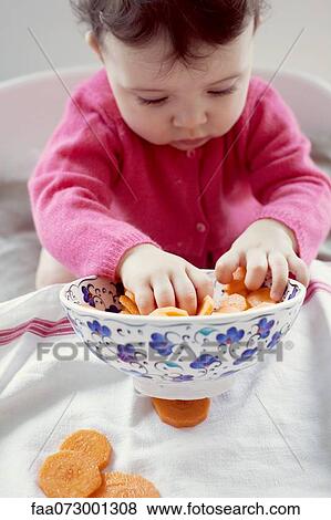 Stock Photo - Infant playing with bowl of carrots. Fotosearch